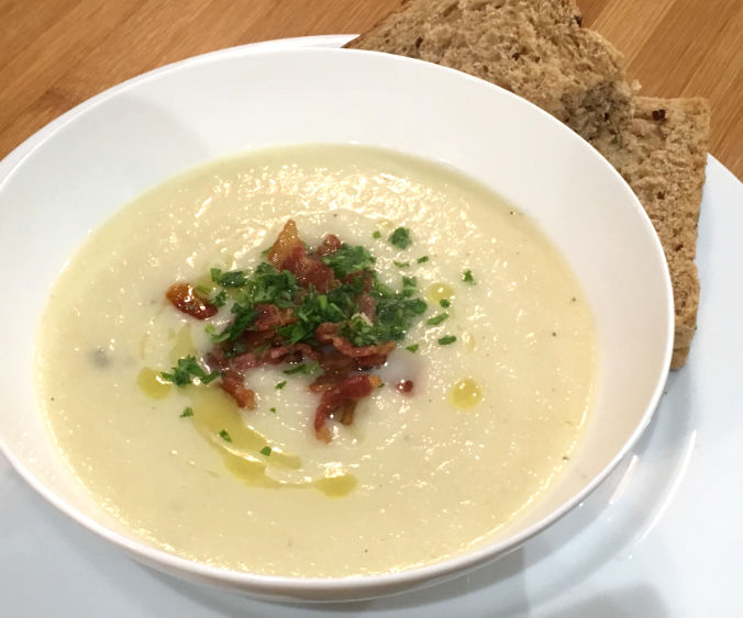 bowl of celeriac soup with bacon and parsley garnish